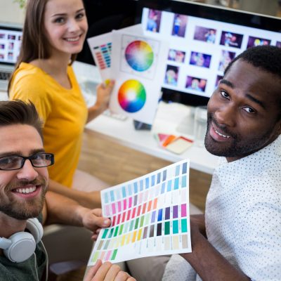 Group of graphic designers holding color chart in office