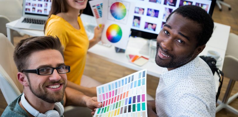 Group of graphic designers holding color chart in office